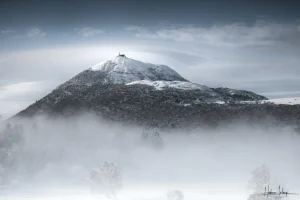Photo d'art du Puy de Dôme recouvert de neige, dans le brouillard et les nuages. Photo d'Art Hadrien Leloup