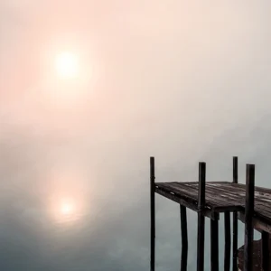 Photographie d'art ponton en bois sur un lac brumeux au lever du soleil, reflets dorés et bleus, ambiance zen et contemplative - Le Seuil des Songes par Hadrien Leloup