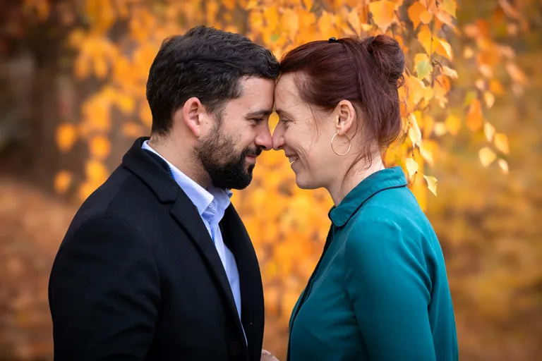 Séance portrait couple automne Hadrien Leloup photographe Séance de portrait de couple en forêt du Puy de Dôme devant un arbre aux feuilles aux couleurs automnales. Photographie prise par Hadrien Leloup photographe à Clermont-Ferrand.